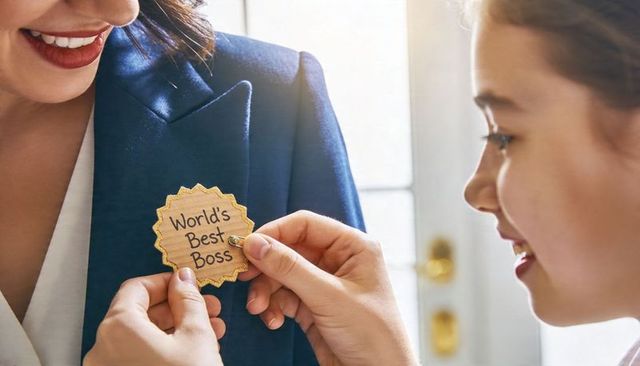 Daughter pinning worlds best boss badge on working mother wearing navy blazer