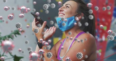 Enthusiastic woman at climbing gym wearing mask with virus overlay