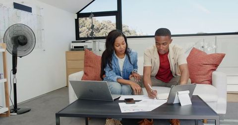 Focused Teamwork in Home Office with Gadgets and Charts