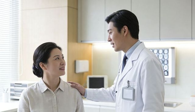Male doctor comforting female patient during clinic consultation showing empathy and care
