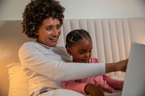 Mother and daughter bonding over laptop at bedtime