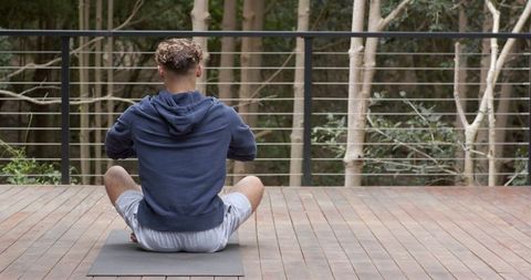 Man Meditating Outdoors on Wooden Terrace in Tranquil Setting