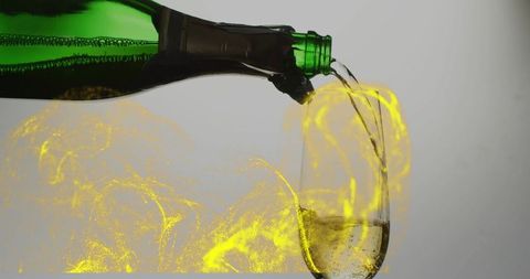 Green bottle pouring sparkling wine into champagne flute with yellow luminescent swirls