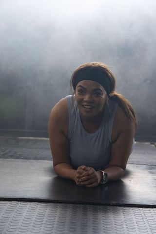 African american woman holding forearm plank wearing headband and smartwatch for core