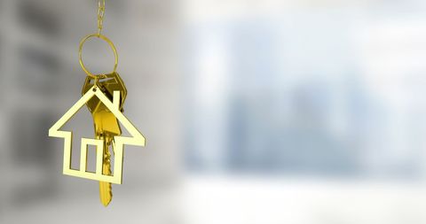 Gold key with house keychain and blurred background