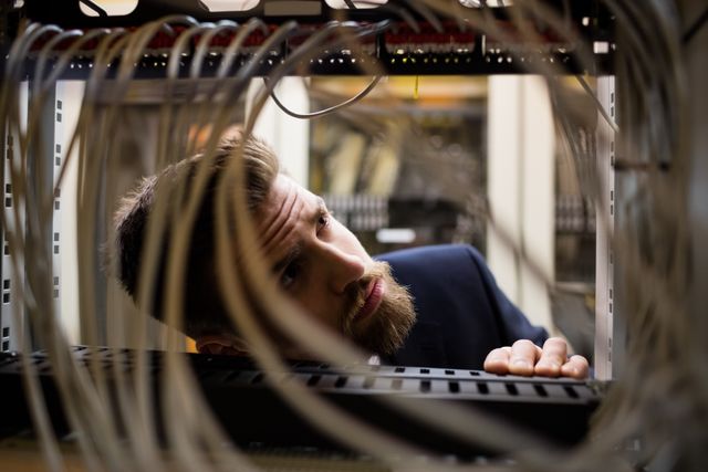 Technician checking cables in a rack mounted server in server room