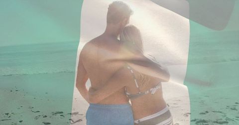 Sunlit couple embracing on sandy shore with turquoise overlay, footprints and romance