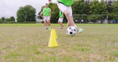 Teen soccer players practicing agility drills in green vests