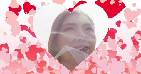 Chinese bride peeking through veil inside heart cutout with pink red confetti background