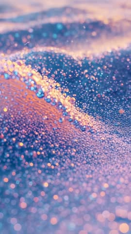 Glittering droplets rolling across shimmering bead ridge in vertical macro motion