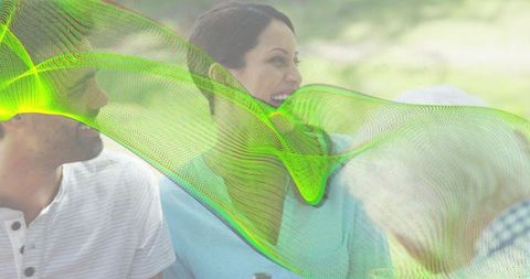 Friends laughing and talking on park bench with green digital wave overlay, casual daylight