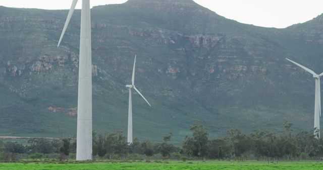 Depicting wind turbines standing tall against a mountainous backdrop, this photo embodies themes of renewable energy and sustainable power generation. Perfect for use in articles or content related to green energy, environmental conservation, clean power sources, and sustainable practices. It conveys a sense of harmony between technology and nature.