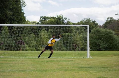African American Goalkeeper Making a Diving Save in Outdoor Match