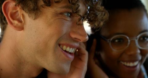 Happy Diverse Couple Sharing Earphones on City Bus