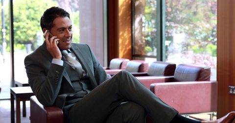 Businessman in suit on phone call in modern office lounge