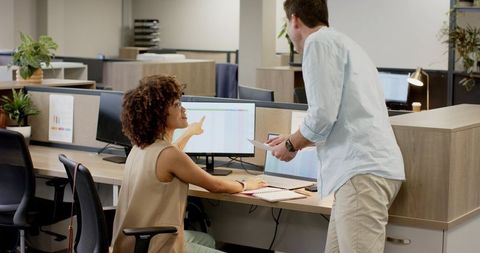 Diverse coworkers discussing data in open-plan office