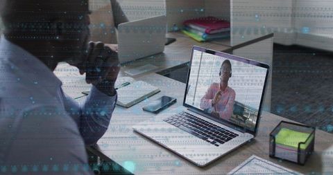Businessman watching laptop during virtual meeting with remote colleague gesturing in office
