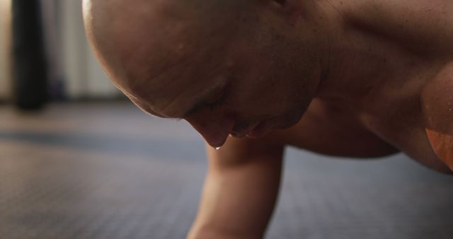 Caucasian muscular shirtless bald man exercising and doing plank. health and fitness training at gym.