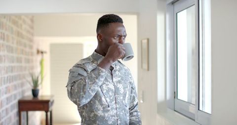 Contemplative Soldier Drinking Coffee at Home Near Window