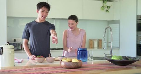 Diverse couple preparing breakfast on modern kitchen island, bright minimalist home