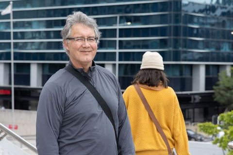 Smiling senior man standing in urban plaza with modern glass building backdrop