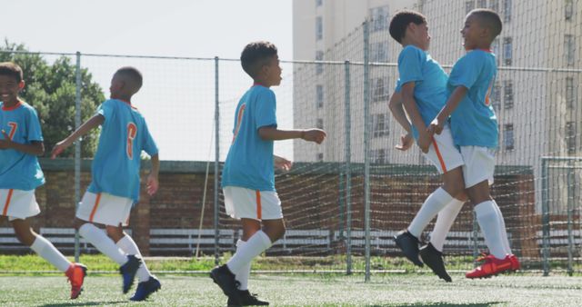 Biracial boys play soccer on a sunny outdoor field. They exhibit teamwork and sportsmanship during a school or community game.