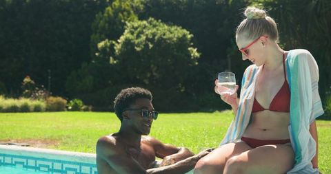 Young Diverse Couple Relaxing at Poolside on Summer Day