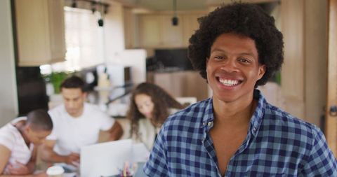 Cheerful Man at Home with Colleagues Working in Background