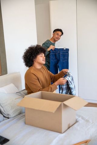 Roommates organizing and unpacking clothes together in bedroom