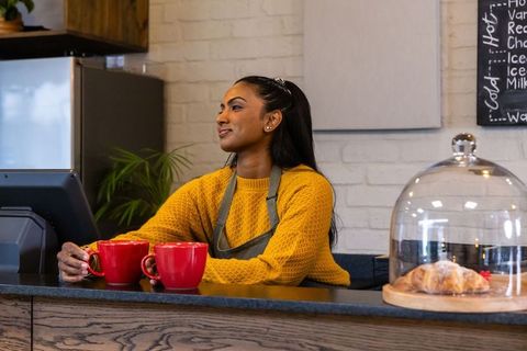 African american barista serving coffee with red mugs at cozy cafe counter