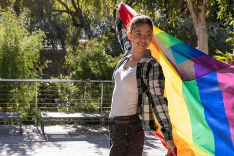 Woman Joyfully Holding Rainbow Flag Outdoors