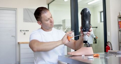 Prosthetics technician adjusting leg prosthetic in modern lab
