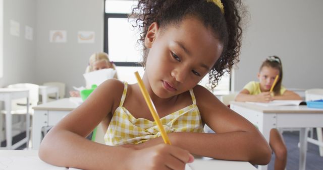 Focused Girl Writing in Classroom with Classmates - Download Free Stock Images Pikwizard.com