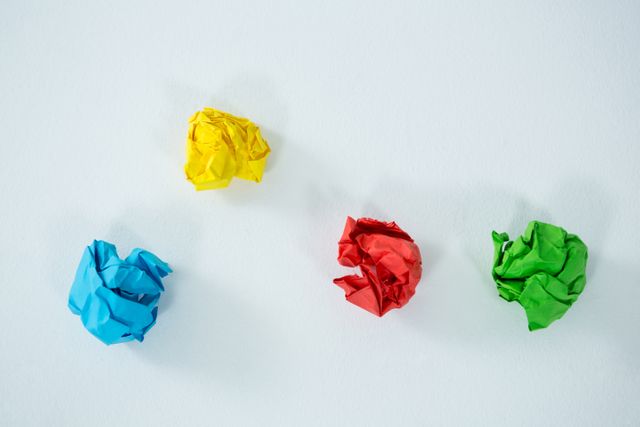 This image features crumpled pieces of paper in yellow, blue, red, and green against a white background. It can be used to represent creativity, brainstorming, or artistic concepts. Ideal for use in design projects, educational materials, or advertisements related to art and creativity.