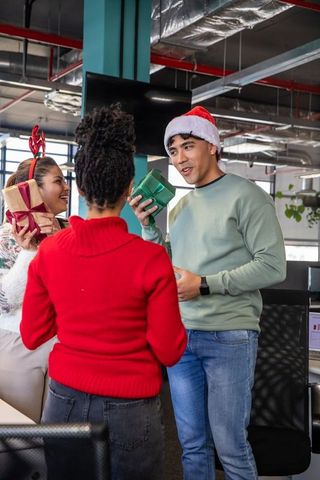 Diverse office team exchanging holiday gifts and celebrating at festive workplace party