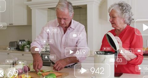 Senior couple cooking together slicing vegetables with multicooker on bright kitchen countertop live