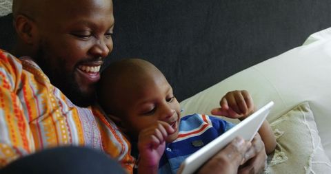 Father and Son Bonding with Tablet on Cozy Bed