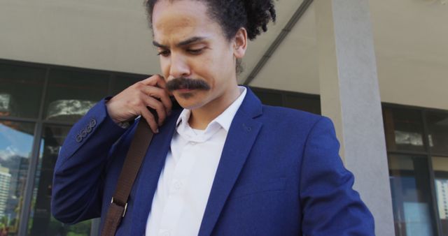 Biracial man with moustache walking on the street and using smartphone. digital nomad, out and about in the city.