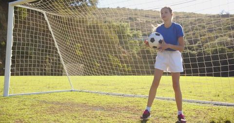 Young Girl Holding Soccer Ball on Grass Field