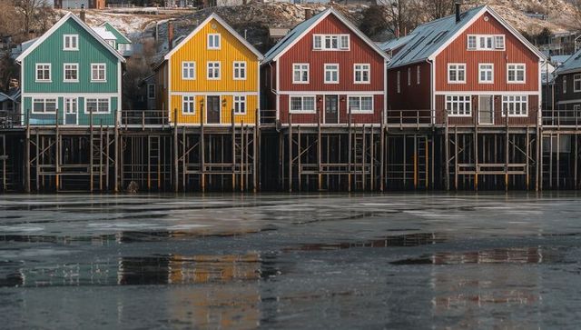 Colorful wooden stilt houses standing on pilings over frozen harbor reflecting winter light