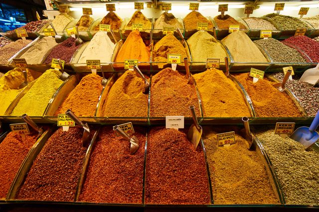 This vibrant scene of colorful spices neatly displayed in a market showcases a diverse array of seasonings and herbs. The vibrant colors and different textures create a visually striking composition, making it suitable for use in culinary blogs, travel articles about markets or exotic food, and advertisements related to cooking and gastronomy. The image evokes a sense of rich aromas and ingredients, perfect for enhancing content on the importance of spices in cooking or culture.