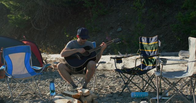 Man Playing Guitar at Camping Site Near River - Download Free Stock Images Pikwizard.com