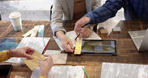 Design Team Comparing Color Swatches and Materials on Rustic Wooden Table with Tablet