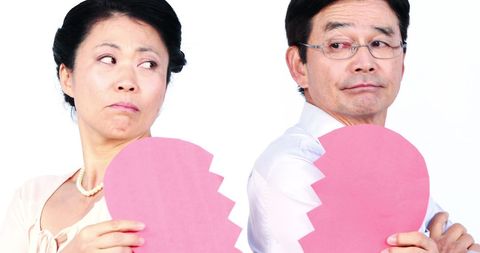 Middle-aged asian couple with broken heart symbolizing relationship problems