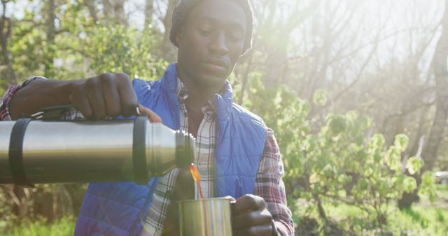 Young Man Pouring Hot Beverage from Thermos in Forest - Download Free Stock Images Pikwizard.com