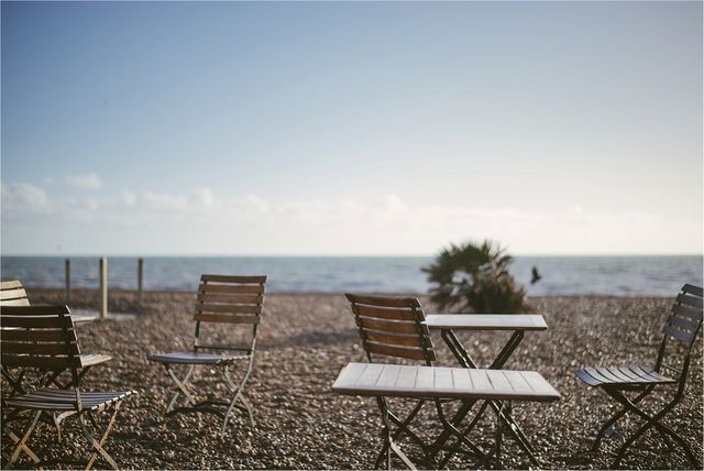 Photo shows outdoor beach cafe with empty chairs and tables, facing the sea under a sunny sky. It is ideal for marketing beach resorts, outdoor dining, travel, tourism, and hospitality promotions. The serene and peaceful setting makes it perfect for capturing a relaxing vibe.
