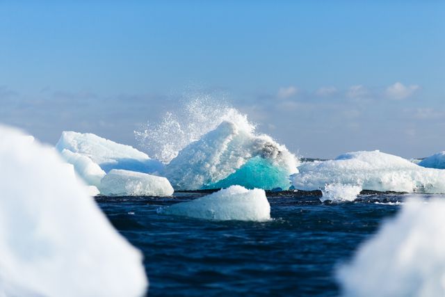 Melting icebergs float in deep blue ocean waters on a sunny day, showcasing effects of climate change. Ideal for environmental campaigns, climate change awareness, educational content, and articles on global warming.
