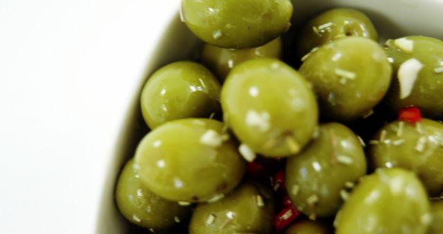 A close-up view of green olives seasoned with garlic and spices, with copy space. Olives are a popular appetizer and ingredient in Mediterranean cuisine.