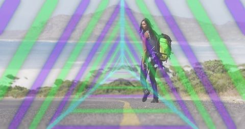 Backpacker walking coastal road looking back wearing striped top and neon triangle overlay