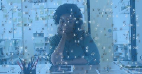 Designer working at studio desk with binary data overlay for digital design concept